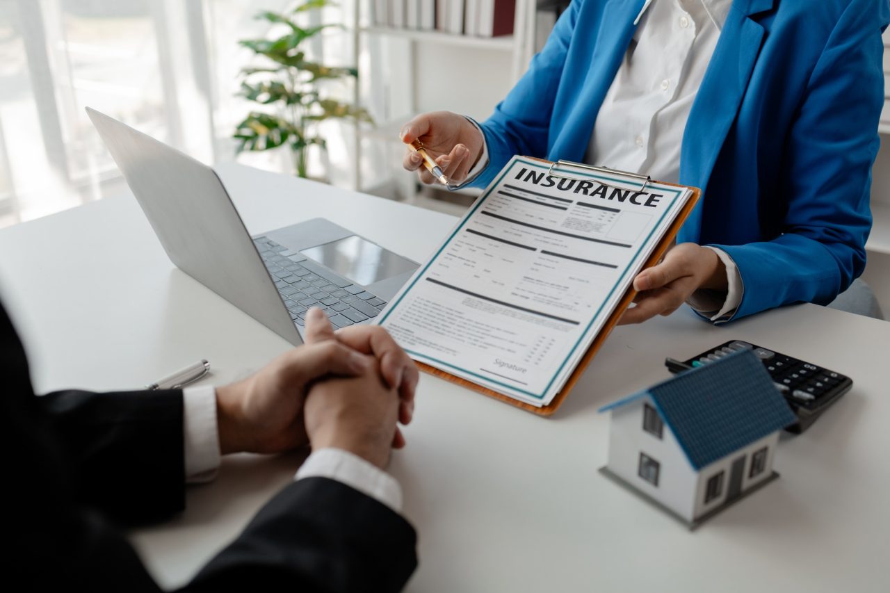 house insurance paperwork a realtor is explaining home insurance documents to a buyer in his office.jpg